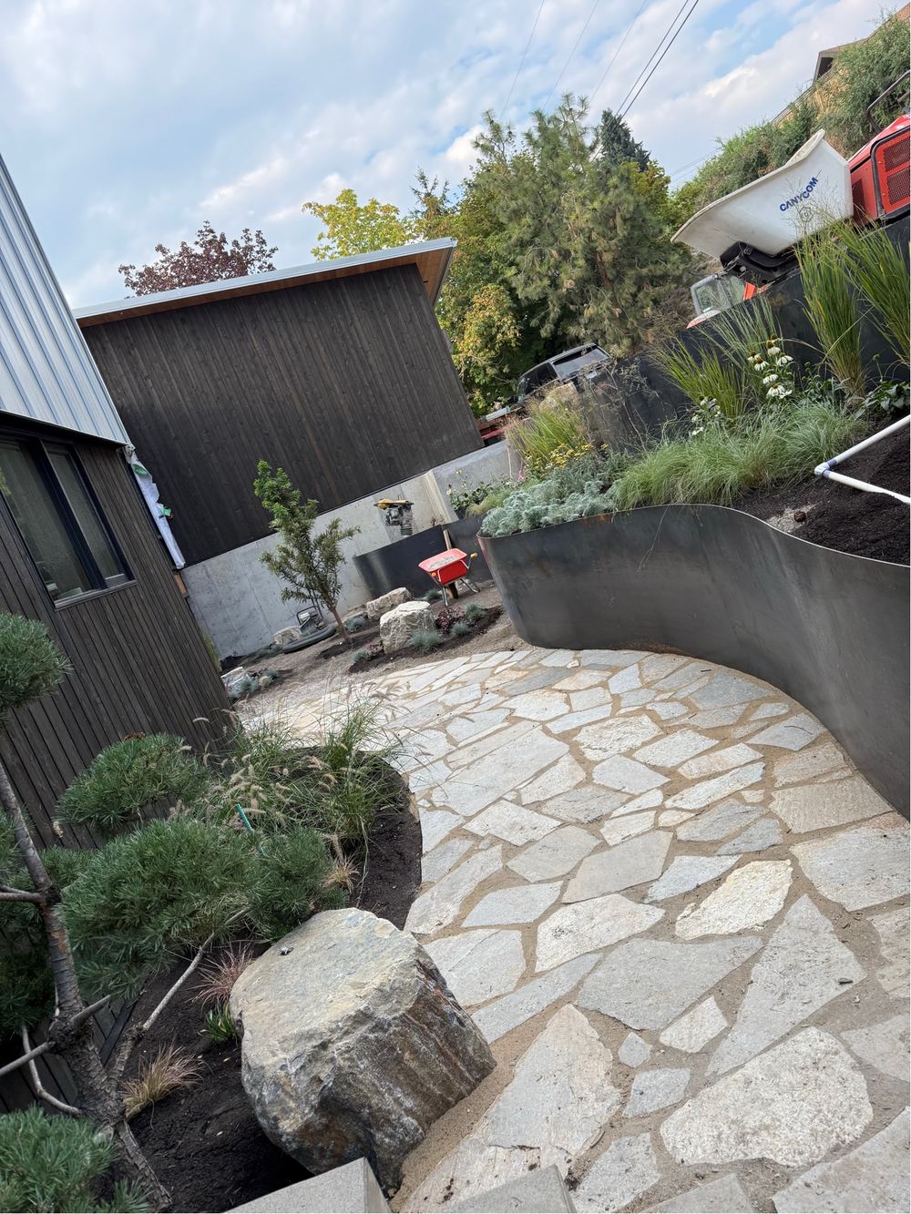 Flagstone patio with placed boulders and steel planter edging